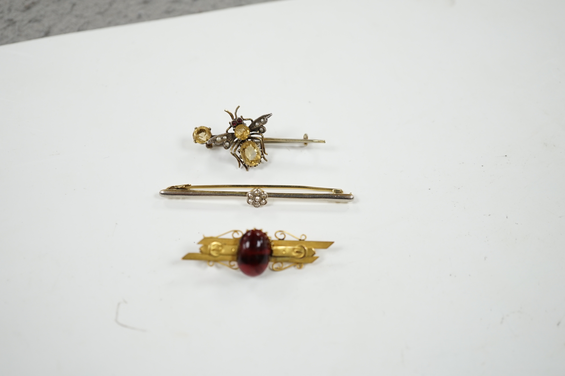 An Edwardian 15ct and diamond cluster set bar brooch, 60mm and two other gem set bar brooches including a bug brooch.